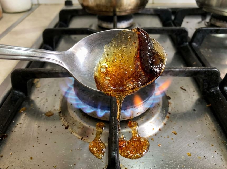 Melted sugar caramelizing on a spoon over a stove flame